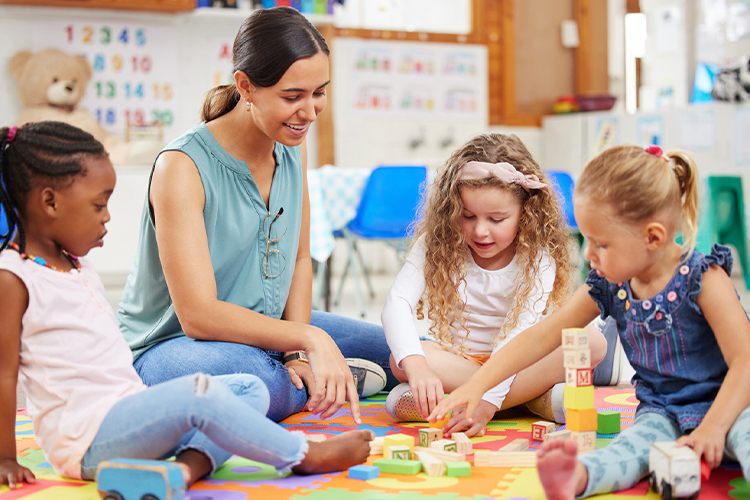 Teacher and kids playing with building blocks in a classroom