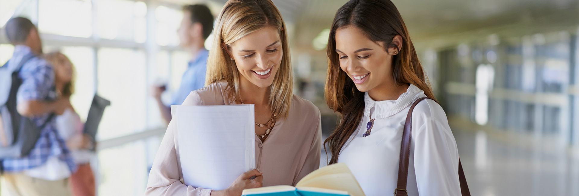 Two women smiling while looking at a book