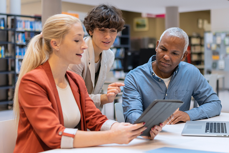 Group of people looking at a digital tablet in the library