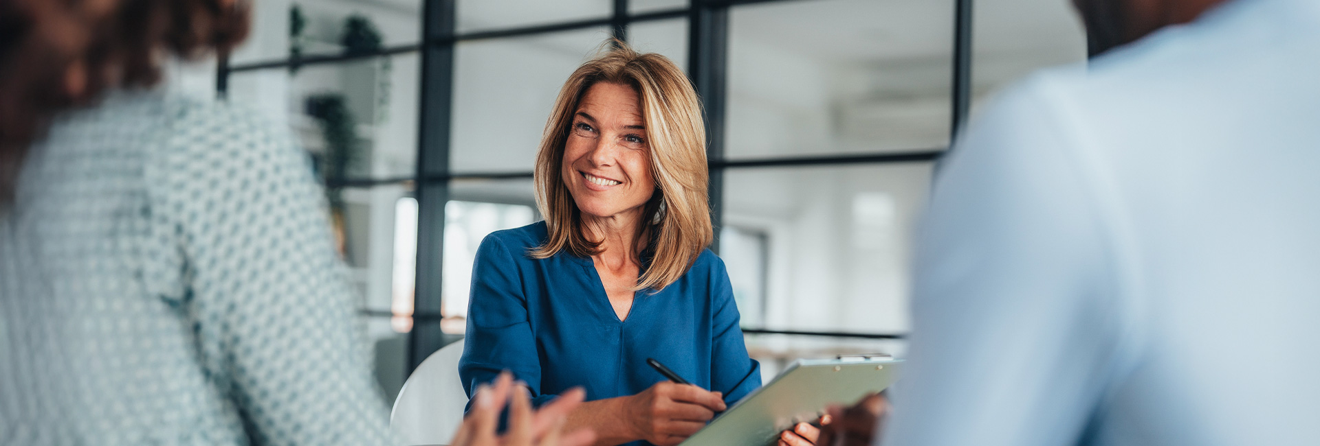 Woman with clipboard speaking with colleagues