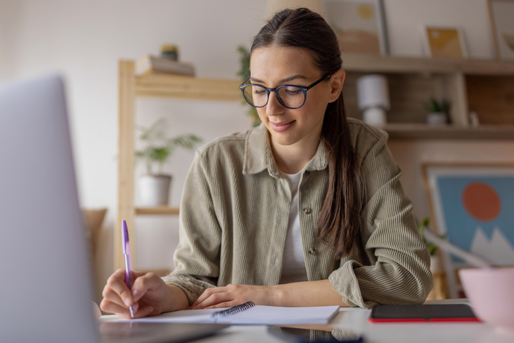 Student taking notes while working from home