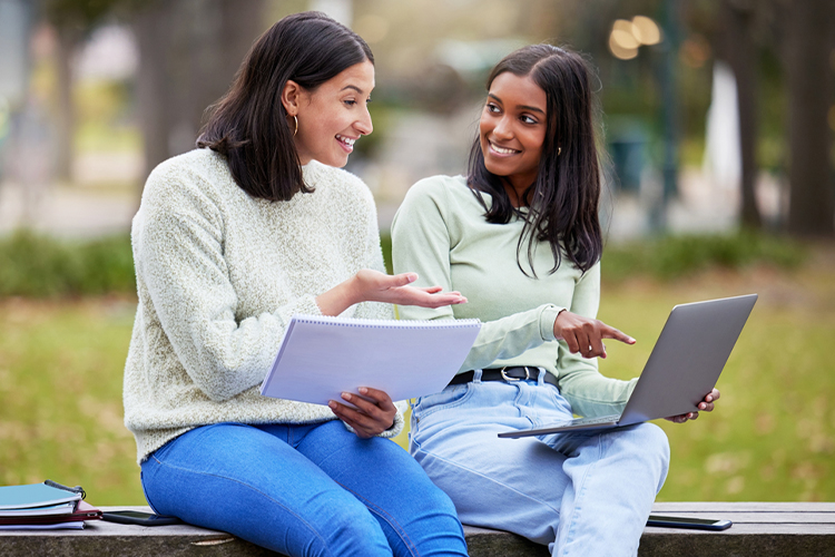 Two students using a laptop outdoors