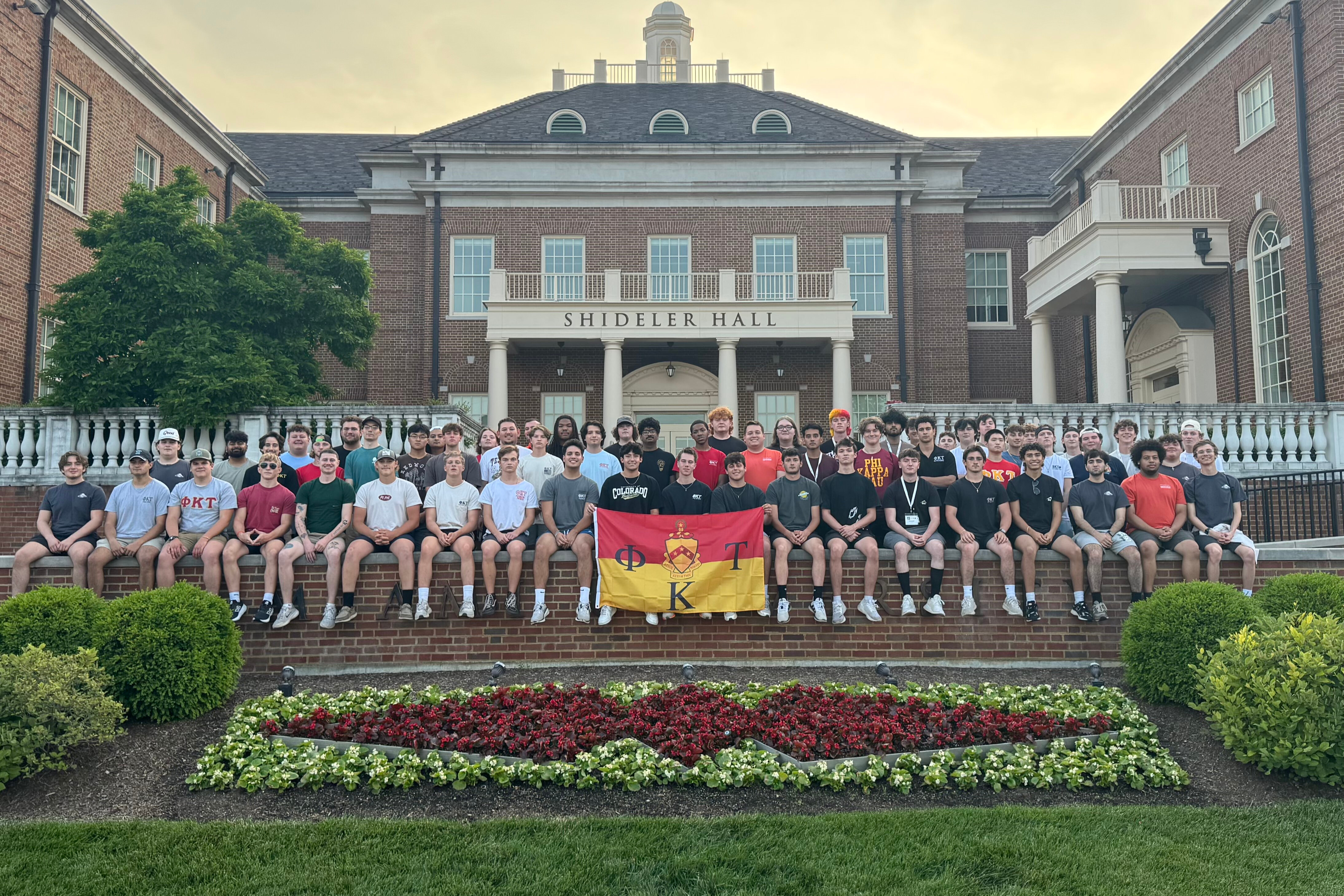 Phi Kappa Tau members sitting on wall in front of Shideler Hall.