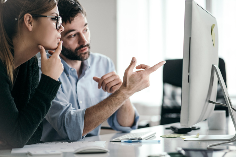 Two people looking at computer screen. 