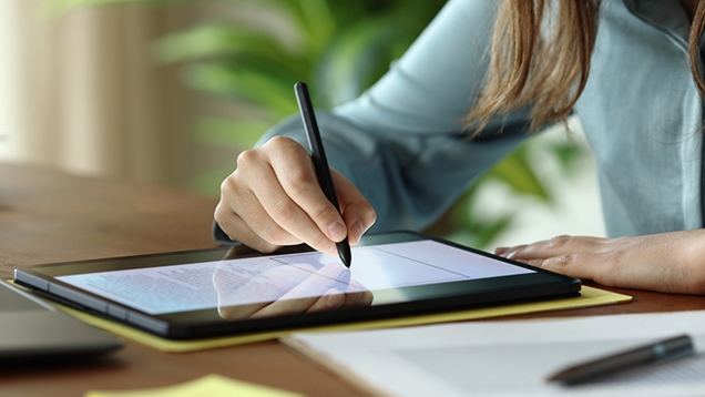Woman signing a document on a digital tablet close up