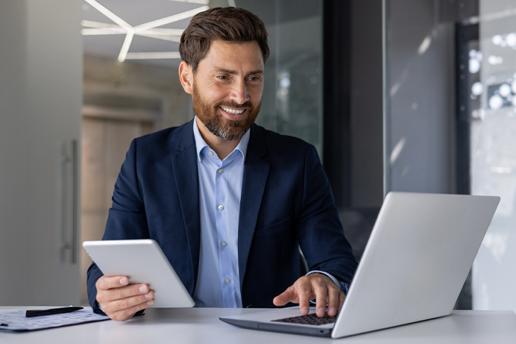 Man using a laptop and digital tablet