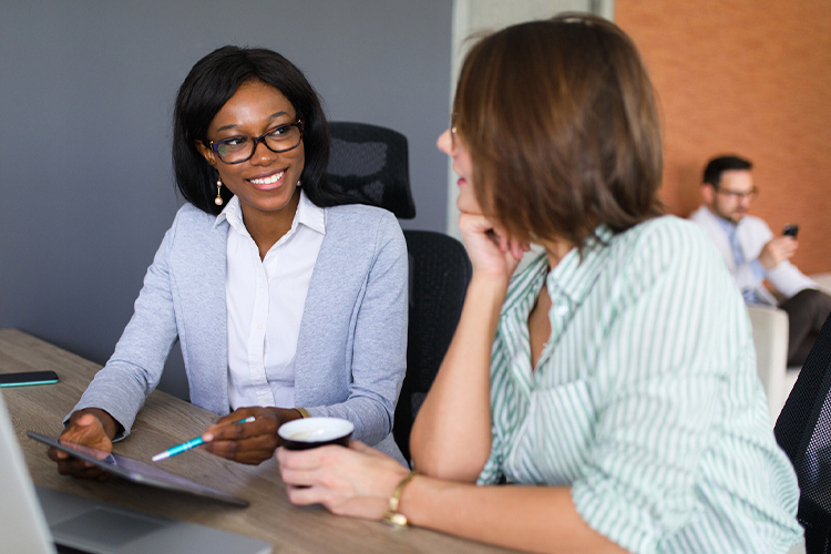 Two women talking while using a digital tablet