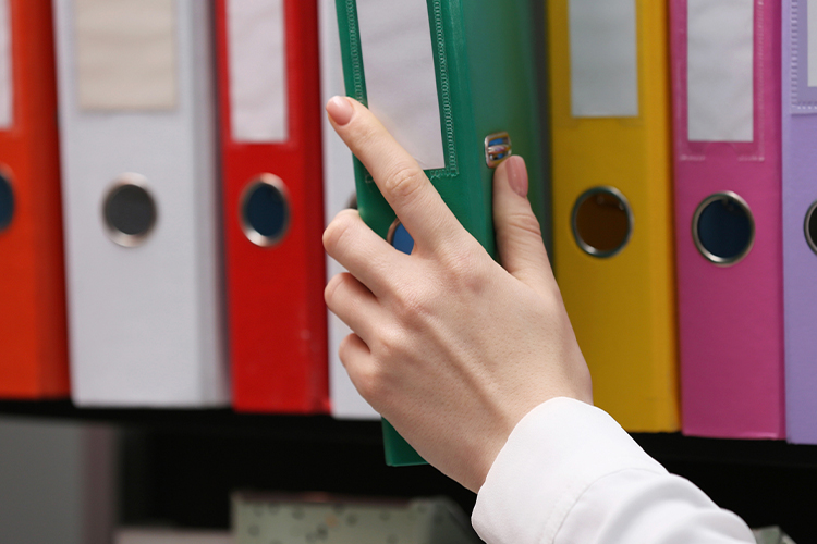 Woman taking folder from shelf close up