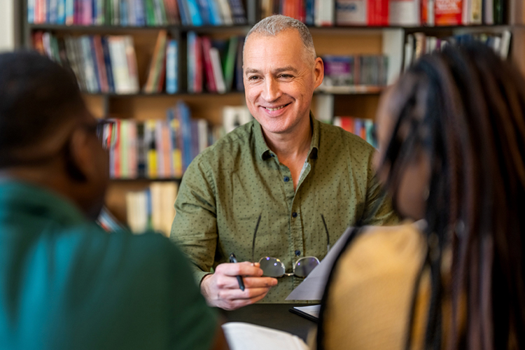 Advisor speaking with students in a library