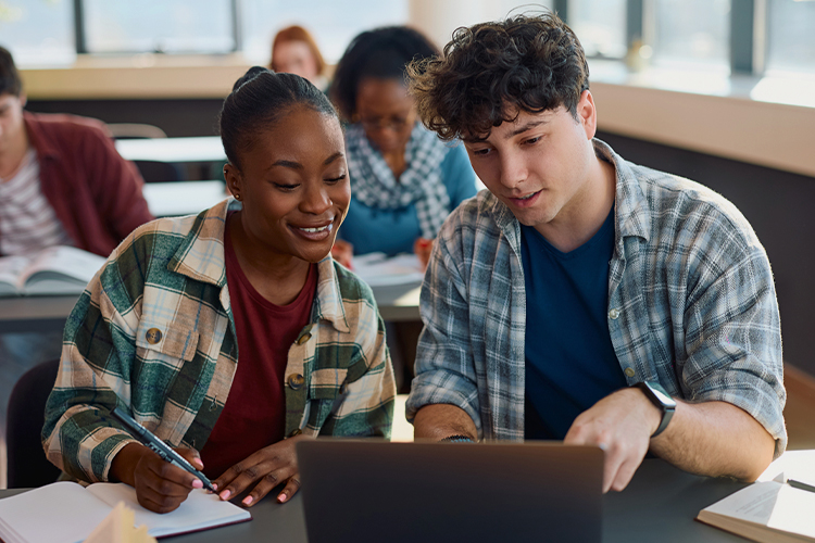 Two students using a laptop in a classroom